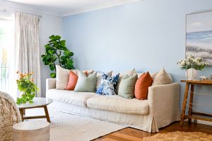 Our client's brief was for this space to have colour and a relaxed coastal vibe to reflect the artwork chosen by our client. Custom made curtains in Arteko Fenton Natural deliver a relaxed vibe softening the look of the Devon Blue feature wall by Wattyl, together with contrasting custom cushions in Unique Fabric's Chivasso rust and sage. The floor rug, white wooden accent side table and Claudine hand knit throw add layers of texture complementing the space. The colours of rust and sage were chosen to reflect the Australian landscape. 