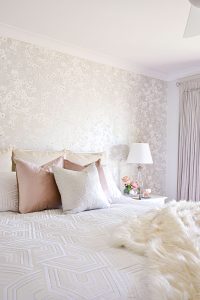 This master bedroom speaks femininity and luxury with its subtle pearlesecent Tiami Mica wall coverings from Romo and custom velvet curtains with brushed silver rods and velvet cushions all by MotzDesigns. This space is all about pattern and texture with a pop of dusky pink. The geometric patterned quilt cover from Private Collection in Bree Silver adds a layer of pattern with the Faux Fur Brushed Tips Throw.